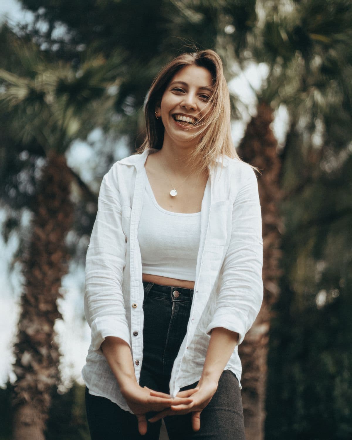 A woman smiling outdoors among palm trees
